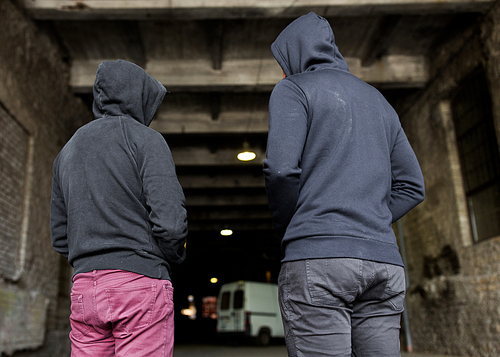 criminal activity, addiction, people and social problem concept - close up of addict men or criminals in hoodies on street