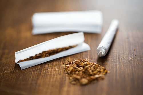 drug use, substance abuse, nicotine addiction and smoking concept - close up of marijuana joint and tobacco