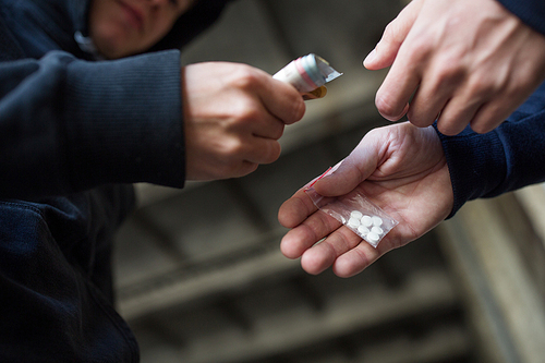 drug trafficking, crime, addiction and sale concept - close up of addict with money buying dose from dealer on street