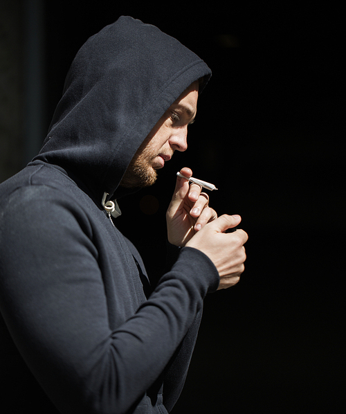 drug use, substance abuse, addiction, people and smoking concept - close up of addict lighting up marijuana joint with lighter