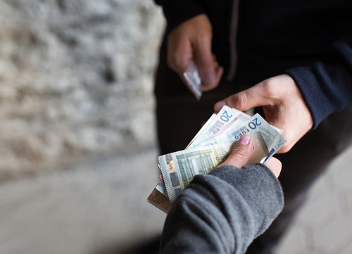 drug trafficking, crime, addiction and sale concept - close up of addict with money buying dose from dealer on street