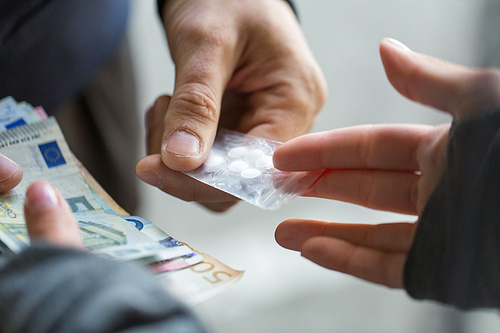 drug trafficking, crime, addiction and sale concept - close up of addict with money buying dose from dealer on street