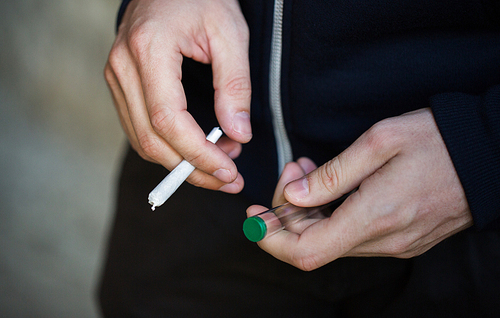 drug use, substance abuse, addiction, people and smoking concept - close up of addict hands with marijuana joint and blunt tube