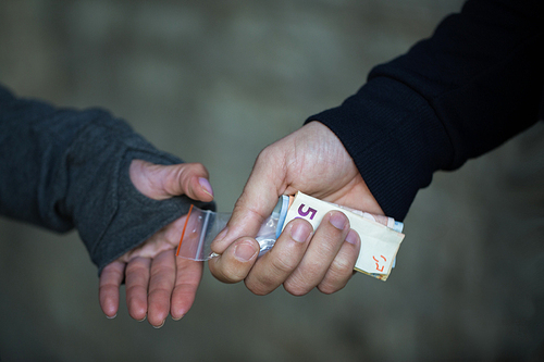 drug trafficking, crime, addiction and sale concept - close up of addict with money buying dose from dealer on street