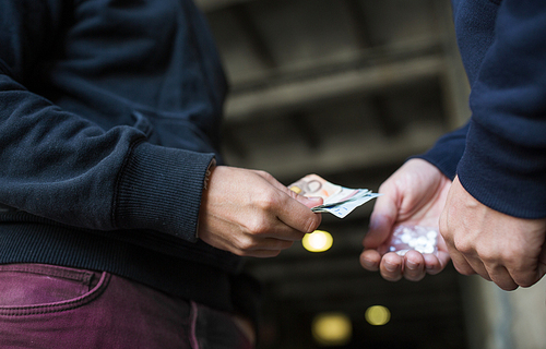 drug trafficking, crime, addiction and sale concept - close up of addict with money buying dose from dealer on street