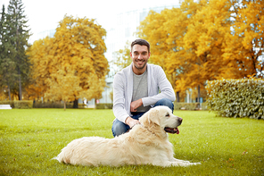 family, pet, animal and people concept - happy man with labrador retriever dog walking in autumn city park