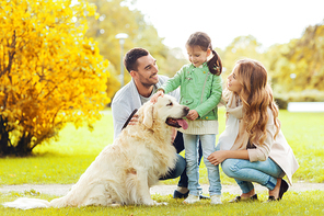 family, pet, domestic animal and people concept - happy family with labrador retriever dog on walk in autumn city park