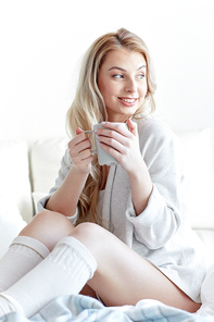 morning, leisure and people concept - happy young woman with cup of coffee or tea in bed at home bedroom