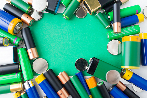recycling, energy, power, environment and ecology concept - close up of alkaline batteries and green blank copy space