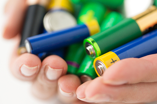 recycling, energy, power, environment and ecology concept - close up of hands holding alkaline batteries heap