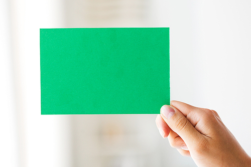 people, information, advertisement and ecology concept - close up of hand holding green paper card