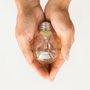 recycling, electricity, environment and ecology concept - close up of hands holding lightbulb or incandescent lamp