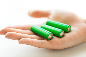 recycling, energy, power, environment and ecology concept - close up of hand holding green alkaline batteries