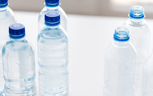 recycling, healthy eating and food storage concept - close up of plastic bottles with pure  water on table