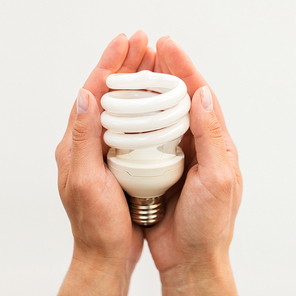 recycling, electricity, environment and ecology concept - close up of hands holding energy saving lightbulb or lamp