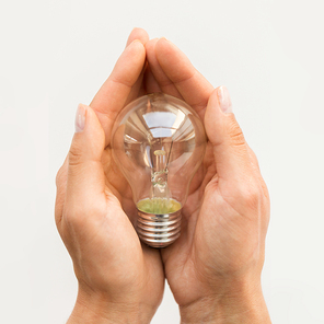 recycling, electricity, environment and ecology concept - close up of hands holding lightbulb or incandescent lamp