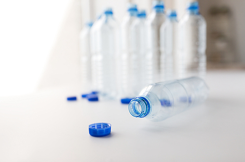 recycling, healthy eating and food storage concept - close up of empty used water bottles and caps on table