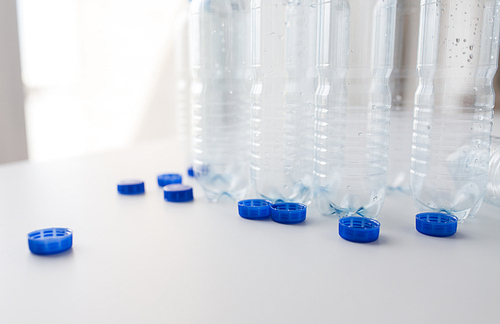 recycling, healthy eating and food storage concept - close up of empty used water bottles and caps on table