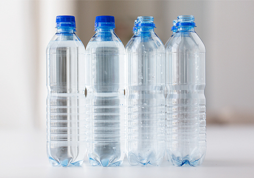 recycling, healthy eating and food storage concept - close up of plastic bottles with pure  water on table