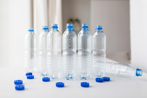 recycling, healthy eating and food storage concept - close up of empty used water bottles and caps on table