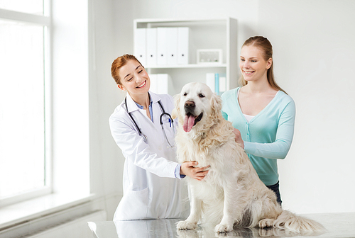 medicine, pet, animals, health care and people concept - happy woman with golden retriever dog and veterinarian doctor at vet clinic