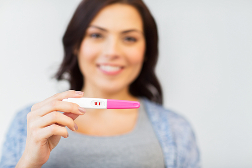 pregnancy, fertility, maternity and people concept - close up of happy woman with positive home pregnancy test