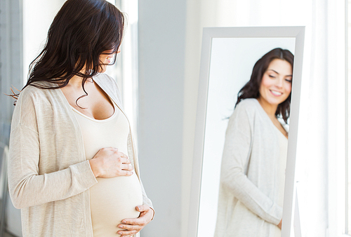 pregnancy, motherhood, people and expectation concept - close up of happy pregnant woman looking to mirror at home