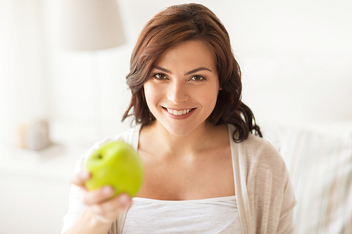 healthy eating,  and people concept - smiling young woman with green apple at home