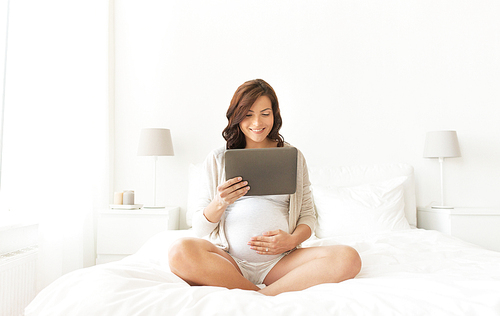 pregnancy, technology, people and expectation concept - happy pregnant woman with tablet pc computer in bed at home