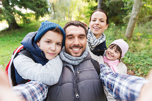 technology, travel, tourism, hike and people concept - happy family with backpacks taking selfie and hiking