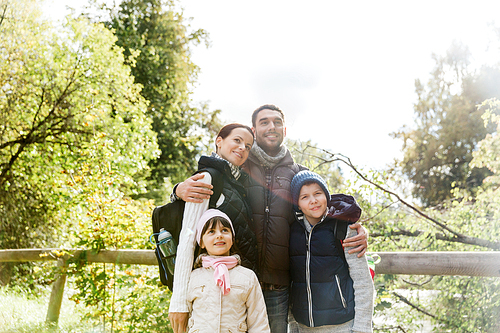 adventure, travel, tourism, hike and people concept - happy family walking with backpacks in woods