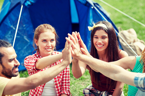 travel, tourism, hike and people concept - group of happy friends with tent making high five at camping