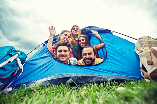 travel, tourism, hike, equipment and people concept - group of happy friends with backpacks in tent at camping