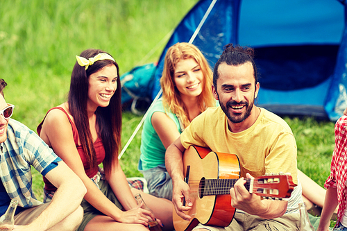 travel, tourism, hike, picnic and people concept - group of happy friends with tent and drinks playing guitar at camping