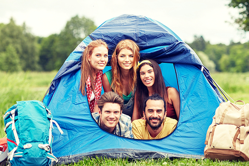 travel, tourism, hike, equipment and people concept - group of happy friends with backpacks in tent at camping