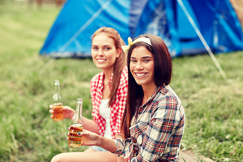 camping, travel, tourism, hike and people concept - happy young women with glass bottles drinking cider or beer at campsite