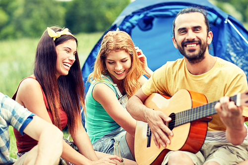 travel, tourism, hike, picnic and people concept - group of happy friends with tent and drinks playing guitar at camping