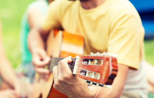 music, leisure and people concept - close up of man playing guitar at camping