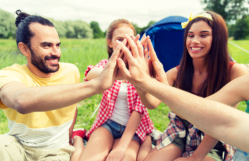 travel, tourism, hike and people concept - group of happy friends with tent making high five at camping