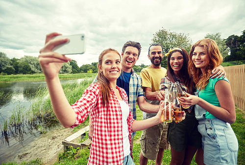 camping, travel, tourism, hike and people concept - happy friends with glass bottles drinking cider or beer and taking selfie by smartphone at camping