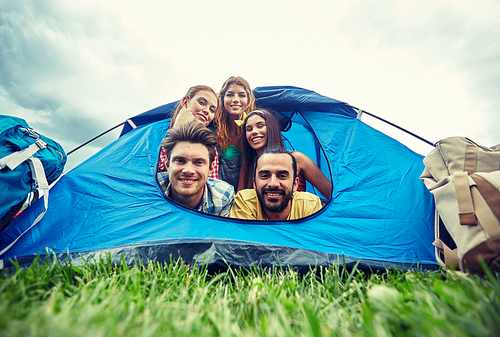 travel, tourism, hike, equipment and people concept - group of happy friends with backpacks in tent at camping