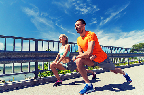 fitness, sport, training and lifestyle concept - smiling couple stretching outdoors