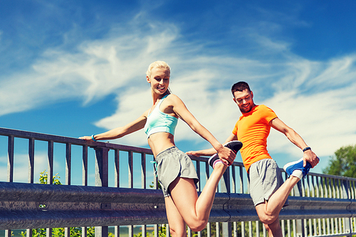 fitness, sport, training and lifestyle concept - smiling couple stretching outdoors