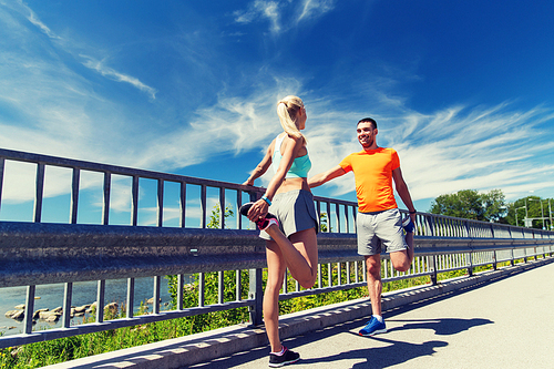 fitness, sport, training and lifestyle concept - smiling couple stretching outdoors