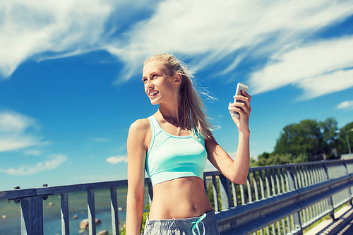 fitness, sport, people, technology and healthy lifestyle concept - smiling young woman with smartphone exercising outdoors