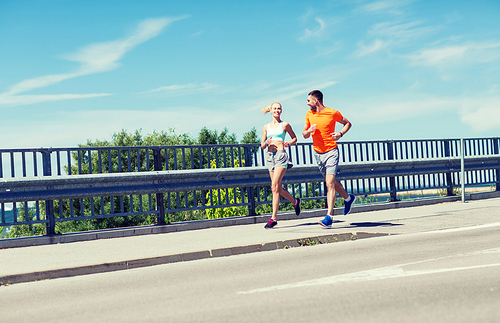 fitness, sport, friendship and healthy lifestyle concept - smiling couple running at summer seaside