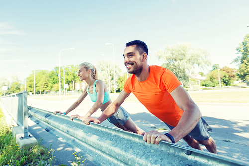 fitness, sport, training and healthy lifestyle concept - close up of happy couple doing push-ups outdoors