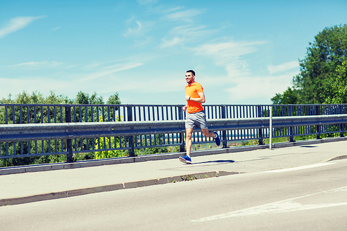 fitness, sport, people, technology and healthy lifestyle concept - smiling young man with heart rate watch running at summer seaside