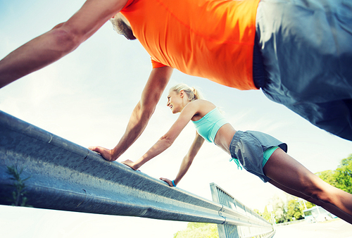 fitness, sport, training and healthy lifestyle concept - close up of happy couple doing push-ups outdoors