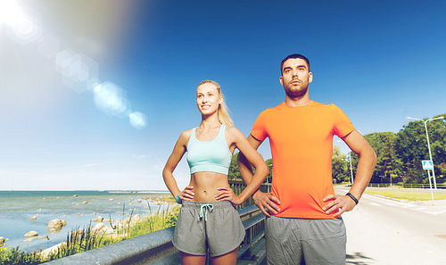 fitness, sport, friendship and healthy lifestyle concept - happy couple exercising at summer seaside